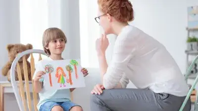 Foster parent looking a Child holding up a drawing 