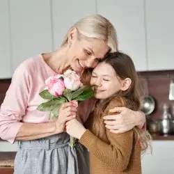 foster mom and foster child hugging with a flower in their hands